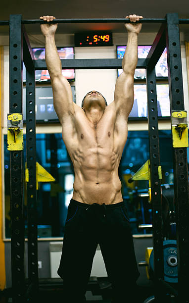 giovane uomo facendo pull-ups in palestra - body building determination deltoid wellbeing foto e immagini stock