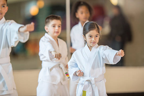 Children Standing in Formation A multi-ethnic group of elementary age children are standing together in formation during their taekwando class. Slective Focus stock pictures, royalty-free photos & images