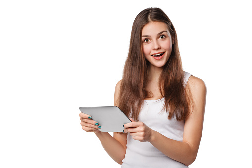 Attractive happy girl in white shirt using tablet. Excited woman with tablet pc, isolated on white background