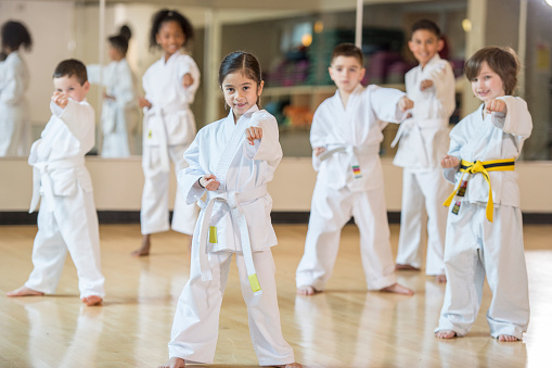 A multi-ethnic group of elementary age children are standing together in formation during their karate class.