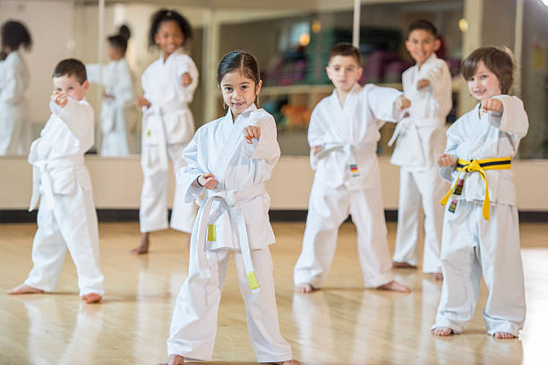 Standing in Formation A multi-ethnic group of elementary age children are standing together in formation during their karate class. martial arts stock pictures, royalty-free photos & images