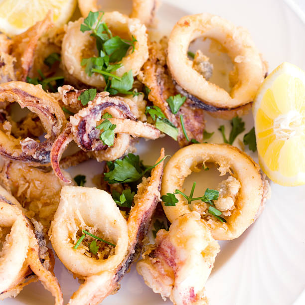 Fresh fried calamary rings A plate of fresh fried calamary rings with lemon calamari stock pictures, royalty-free photos & images