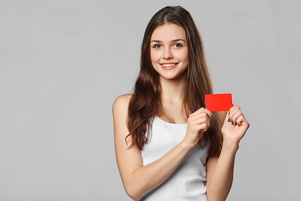 mujer sonriente mostrando en blanco tarjeta de crédito en blanco camiseta aislado - greeting card holding women credit card fotografías e imágenes de stock