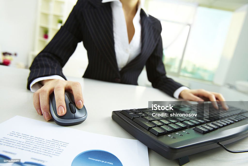 Working in office Image of female hands pushing keys of a computer mouse and keyboard with papers near by Business Stock Photo