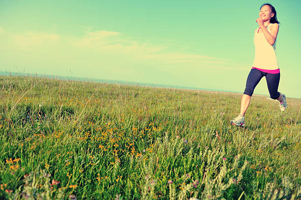 Runner athlete  running on  sunny  grass field. woman fitness jogging workout wellness concept.