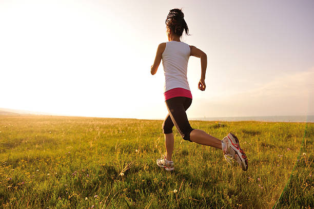Runner athlete  running on sunrise/sunset grass field. woman fitness jogging workout wellness concept.