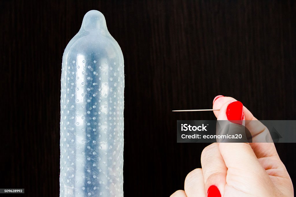 Safe sex versus unprotected sex Inflated condom and a hand with a needle Adult Stock Photo