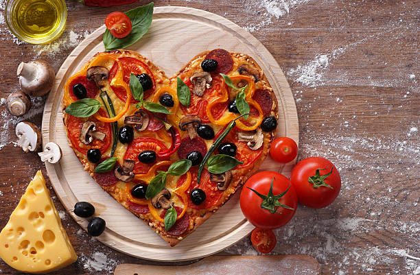istock Pizza heart shape with ingredients on vintage boards. 509633316
