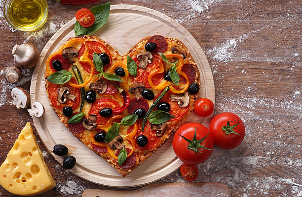 Pizza heart shape with ingredients on vintage boards. stock photo
