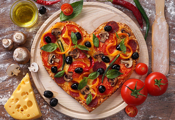 istock Pizza heart shape with ingredients on vintage boards. 509633618