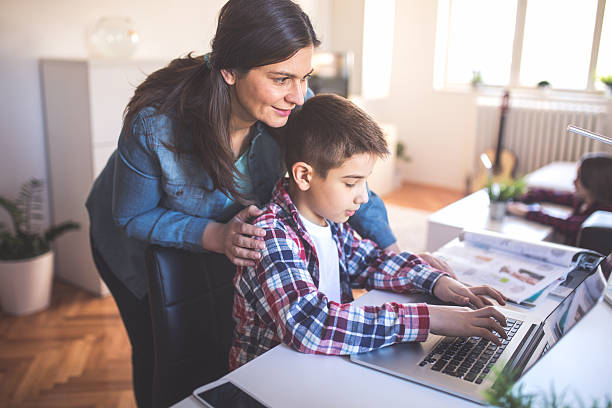 New genration Mother helps son how to use a lap top and internet home schooling homework computer learning stock pictures, royalty-free photos & images