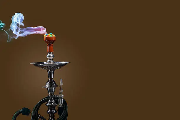 Smoking hookah with fruit head on dark background