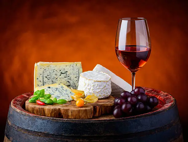 Glass of rose wine with grapes and gorgonzola blue cheese,  camembert and brie