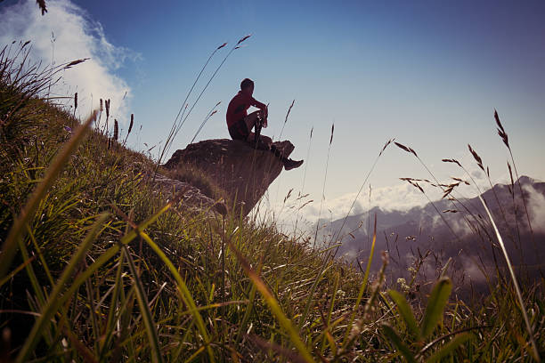 Relax on the rock A man sit on a rock relaxing after a mountain walk. strada sterrata stock pictures, royalty-free photos & images