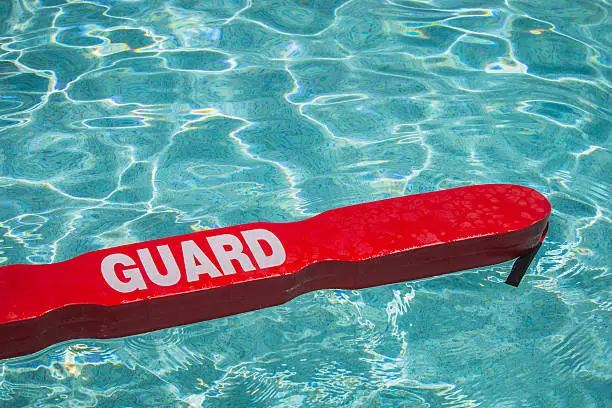 A close up shot of a life guards red rescue tube floating in a pool.