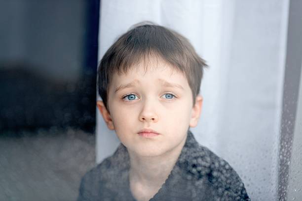 istock Depressed 7 years boy child looking out the window. 509665794