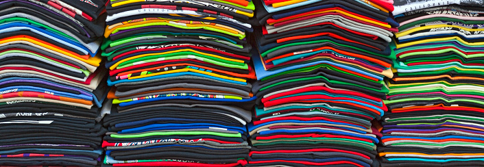 Stacked row of colorful souvenir t-shirts. Horizontal.