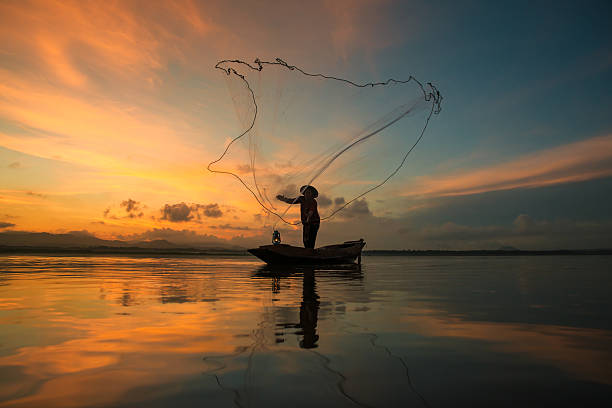 pêcheur à la pêche sur le lac en journée, en thaïlande. - filet de pêche industrielle photos et images de collection