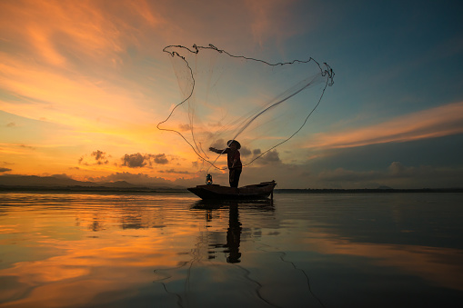 Fisherman fishing at lake in Morning, Thailand.