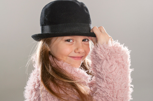 Portrait of a beautiful little smiling girl with a black hat