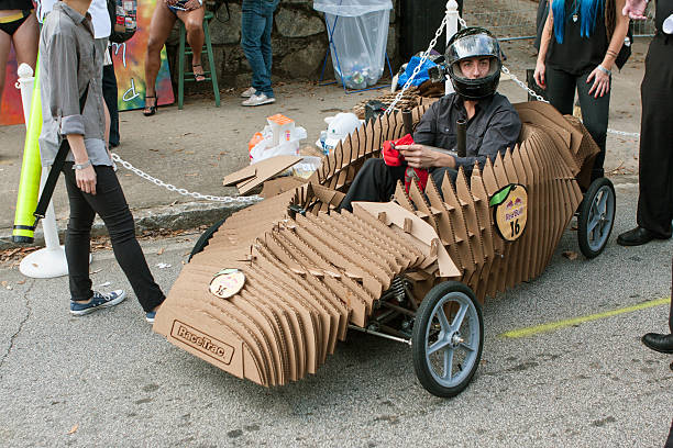 Cardboard Vehicle Driver Ready To Race In Soap Box Derby Atlanta, GA, USA - October 24, 2015:  A driver sits in his homemade vehicle made of cardboard as he waits for his run in the Red Bull Soap Box Derby on North Avenue in Atlanta, GA. soapbox cart stock pictures, royalty-free photos & images
