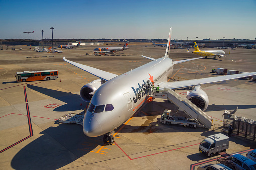 Tokyo, Japan - February 11, 2016: A Jetstar Airways Boeing 787 being prepared for a flight to Melbourne at Narita Airport's Terminal 3, with other airport traffic visible behind it. 