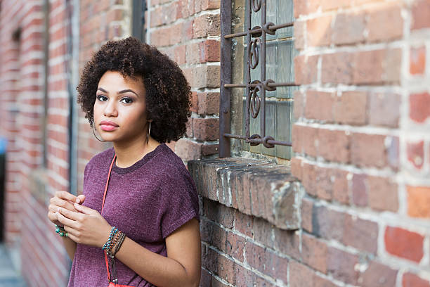 Young, serious African American woman (19 years) standing outside building.