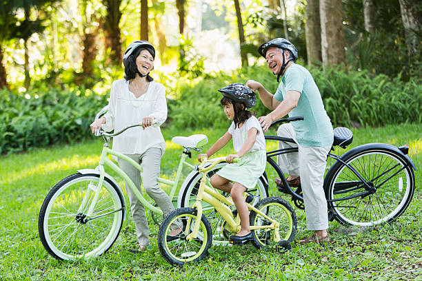 маленькая девочка, езда велосипеды с бабушкой и дедушкой - grandmother action senior adult grandparent стоковые фото и изображения