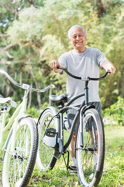 Asian man with bicycle Senior Asian man (60s) with bicycle. man 60s bicycle stock pictures, royalty-free photos & images
