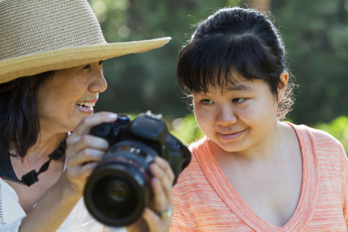 Mature Japanese woman (60s) showing photo on camera to autistic daughter (20s).