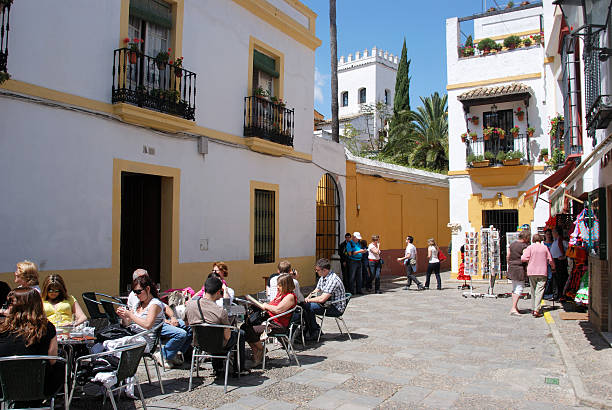 Pavement cafe in the old town, Seville. Seville, Spain - April 12, 2008: Pavement cafes in the Barrio Santa Cruz district (old town) with tourists enjoying the setting, Seville, Seville Province, Andalucia, Spain. santa cruz seville stock pictures, royalty-free photos & images