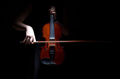Woman playing on violin on black background