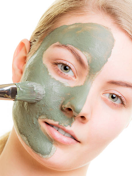 istock Woman applying with brush clay mud mask her face 509709238