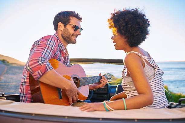 istock Young man playing on guitar during roadtrip 509712172