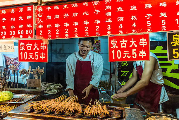 Wangfujing snack street - Beijing Beijing, China - October 13, 2013: Market vendors at Wangfujing snack street offer their customers a very wide variety of foods from their street food stalls. wangfujing stock pictures, royalty-free photos & images