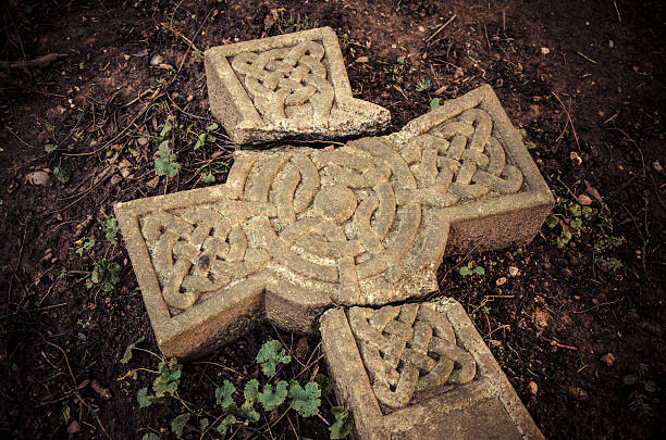 Ancient broken Celtic cross laying on the ground at an English graveyard.