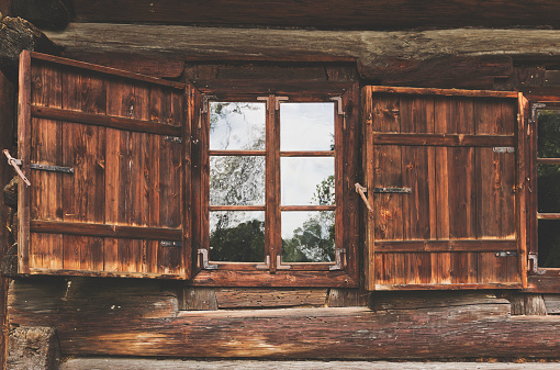 Old wooden window with shutters of an old small wooden cottage in Malopolskie Province, Poland.