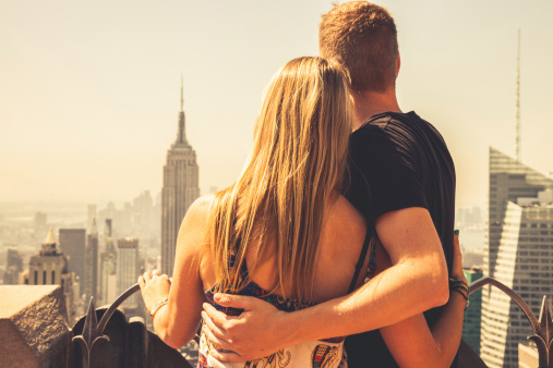 Young couple in visit to New York posing on the top of a building.