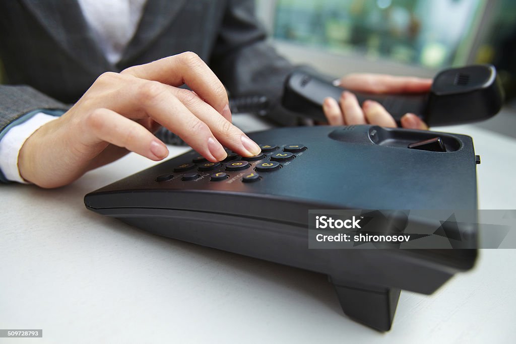 Calling Female hand holding phone receiver and dialing number Business Stock Photo