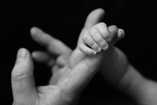A close up image of a newborn baby's tiny hand gripping dad's finger.