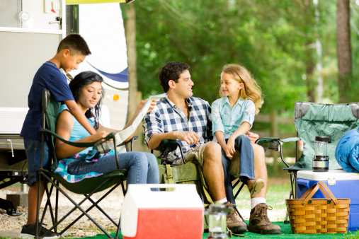 Family of four on vacation. They have parked their motor home at a national park campground for the day. Family discusses the day's plans together.