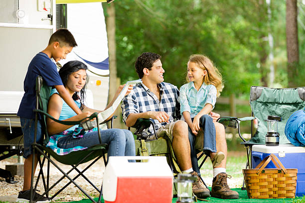 Family summer vacation. Motor home parked at national park campground. Family of four on vacation. They have parked their motor home at a national park campground for the day. Family discusses the day's plans together. travel destinations 20s adult adventure stock pictures, royalty-free photos & images