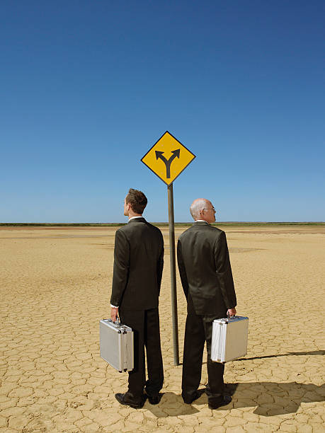istock Businessmen With Briefcases Standing By Road Sign In Desert 509761179
