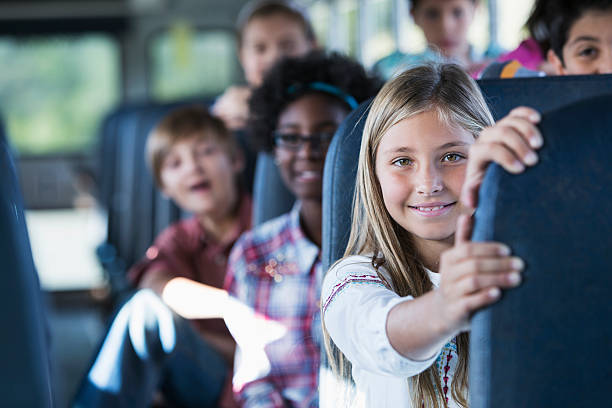 Children riding school bus Children (10-12 years) riding school bus.  Focus on girl in foregound. school buses stock pictures, royalty-free photos & images