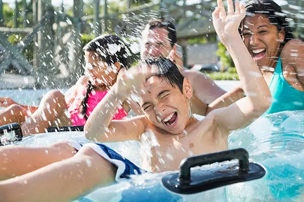 Multi-ethnic family with two children having fun at water park.  Main focus on boy (9 years).