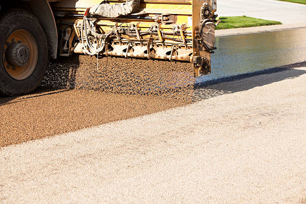 Chip Sealing Asphalt Pavement Street with Crushed Rock Crushed rock is being applied to an seal coated street. The seal coat (asphalt tar) has been sprayed onto the surface by a leading vehicle. This is the process of chip sealing a street, chipsealing is a lower cost resurfacing alternative. The bottom left is the opposite side of the street which has already received a coating of rock. tar stock pictures, royalty-free photos & images