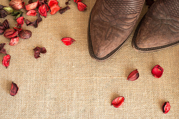 Cowboy boots lined up next to a wooden horse barn wall.