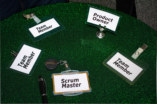 Scrum master, Product owner and team member  Badgeson a round daily scrum table in an agile project