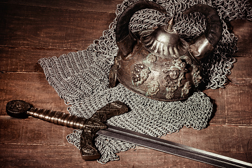 A real helmet, sword and coat of mail Viking on wooden background. A stylized vintage image.