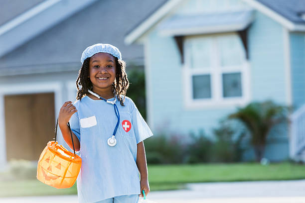 Little boy in surgeon costume on halloween Little African American boy (6 years) going trick or treating on halloween, dressed as doctor, standing outdoors in front of house, smiling stage costume stock pictures, royalty-free photos & images